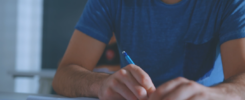 Photo d'un étudiant tenant un critérium au-dessus d'un cahier.