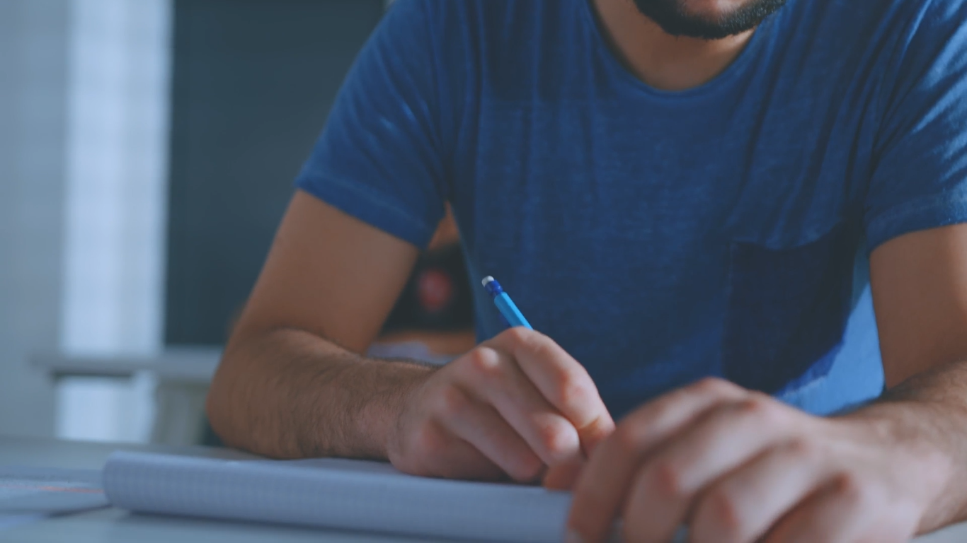 Photo d'un étudiant tenant un critérium au-dessus d'un cahier.